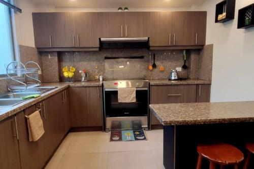 a kitchen with wooden cabinets and a stove top oven at Bonita casa en sector residencial al norte de Loja in Loja