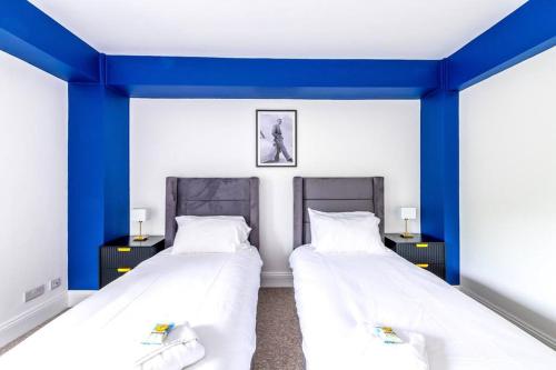 two beds in a room with blue walls at Modern Skyfall with FREE PARKING for Families & Business by Prescott Apartments in Bristol