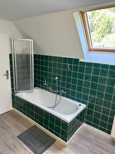 een groen betegelde badkamer met een bad en een raam bij Home of Oasis in Surwold