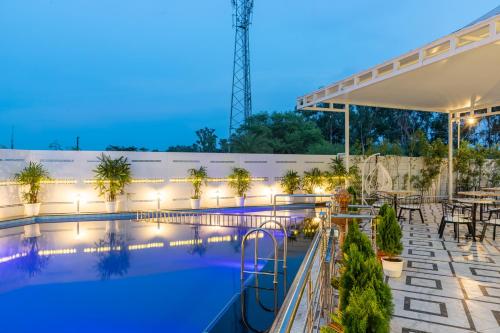 a pool at night with tables and chairs at Hotel Caesars Palace in Bhopal