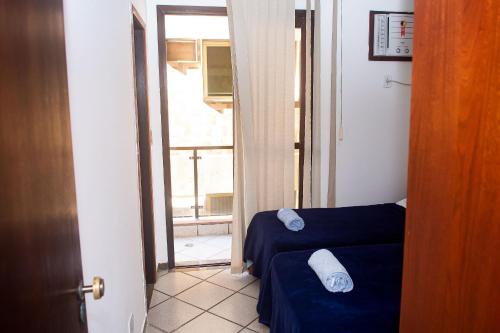a room with two beds and a door with a window at Lindo e bem localizado 3 quartos de frente p/ Mar - Praia do Forte - CF06 in Cabo Frio