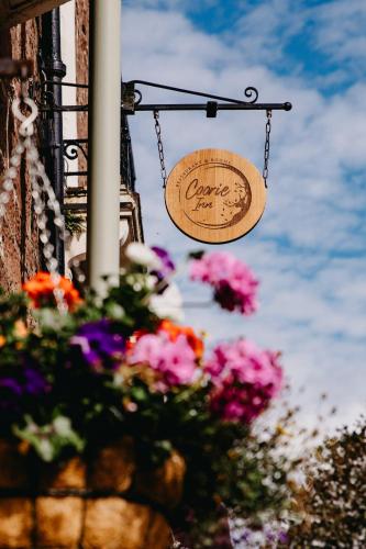 a sign hanging on a chain next to flowers at Coorie Inn Restaurant and Rooms in Crieff
