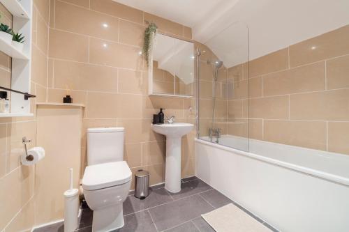 a bathroom with a toilet and a sink and a bath tub at Arte Stays- 3-Bedrooms 2-Bathrooms Garden Spacious House London, Stratford, Free Parking, 6 min walk Elizabeth Line, Weekly or Monthly stays, Serviced accommodation - 7 guests in London