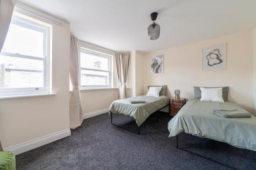 a bedroom with two beds and a window at Arte Stays- 3-Bedrooms 2-Bathrooms Garden Spacious House London, Stratford, Free Parking, 6 min walk Elizabeth Line, Weekly or Monthly stays, Serviced accommodation - 7 guests in London