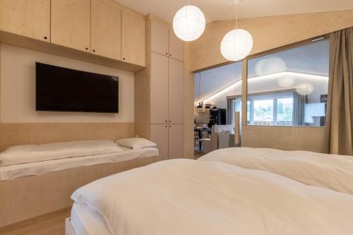 a bedroom with two beds and a flat screen tv at Die Alte Gerberei - La Vecchia Conceria OG2 in Monguelfo