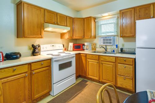a kitchen with wooden cabinets and a white stove top oven at Quaint Cody Cottage with Grill Walk to Downtown! in Cody