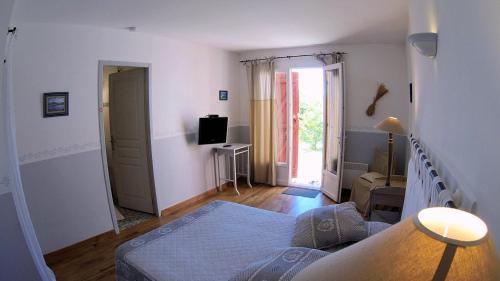 um quarto com uma cama e uma televisão em La Farigoule (Chambres d'Hôtes) em Baudinard