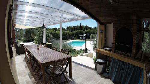 um pátio com uma mesa e vista para uma piscina em La Farigoule (Chambres d'Hôtes) em Baudinard
