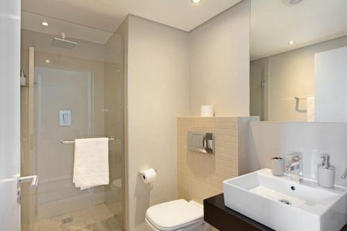 a bathroom with a sink and a toilet and a mirror at Modern 3 Bed Apartment Blouberg in Cape Town