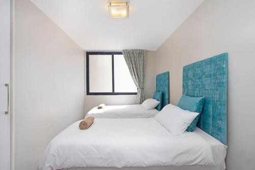 two beds in a white room with a window at Modern 3 Bed Apartment Blouberg in Cape Town