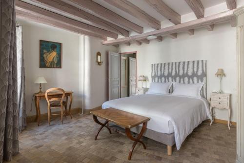 a bedroom with a white bed and a table at La Chaumière in Ousson-sur-Loire