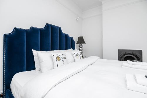 Cama blanca con cabecero azul y almohadas blancas en 4 BR Edwardian family house wgarden, Notting Hill, en Londres