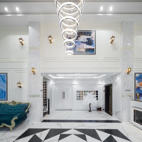 a lobby with a blue couch and a chandelier at Hotel Caesars Palace in Bhopal