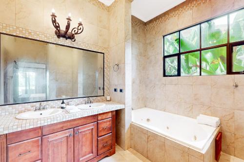 W łazience znajdują się 2 umywalki, wanna i lustro. w obiekcie Villa Coral w mieście Playa Conchal