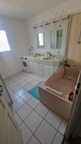 une salle de bain avec deux lavabos et une baignoire dans l'établissement Maison 2 chambres à 5 mn du circuit des 24 heures du Mans proche toute commodités, à Arnage