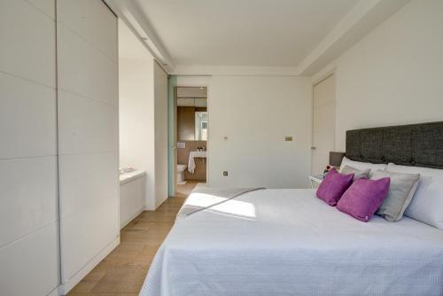 biała sypialnia z dużym łóżkiem z fioletowymi poduszkami w obiekcie Chic 1BR Central London Retreat w Londynie