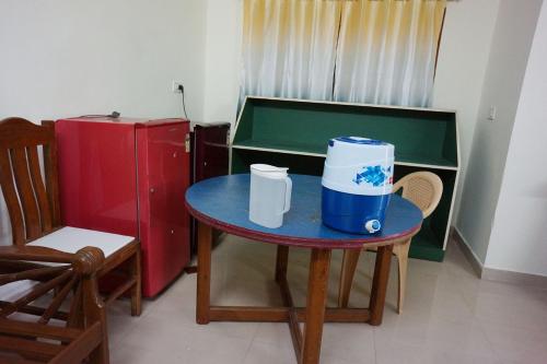 um quarto com uma mesa e uma pequena mesa com um frigorífico em VPR Cottage em Yelagiri