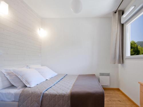 a bedroom with a bed with white walls and a window at Lagrange Vacances Les Chalets d’Ax in Ax-les-Thermes