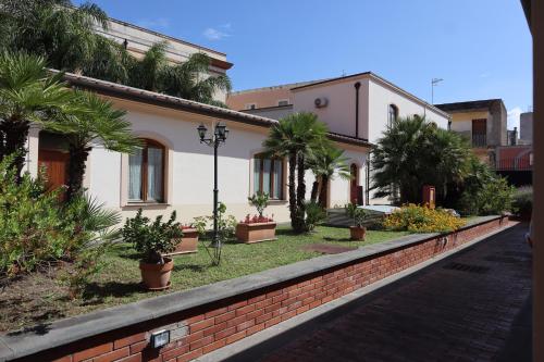 a house with palm trees and a brick wall at Pompei Hostel Deluxe in Pompei