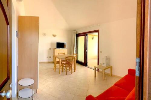 a living room with a red couch and a table at Casa Smeralda - Piscina e vista sul Mare! in Trinità dʼAgultu