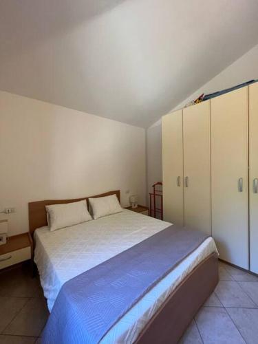 a bedroom with a large bed and white cabinets at Casa Smeralda - Piscina e vista sul Mare! in Trinità dʼAgultu