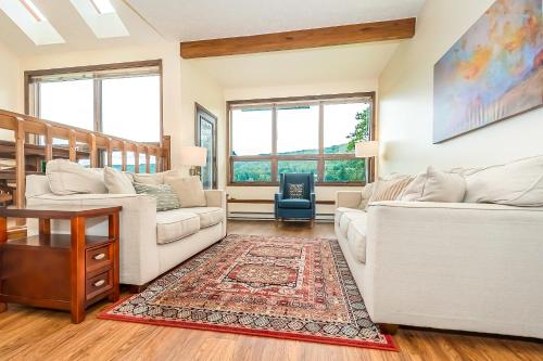 a living room with two white couches and a rug at Ski Harbor 19 in McHenry