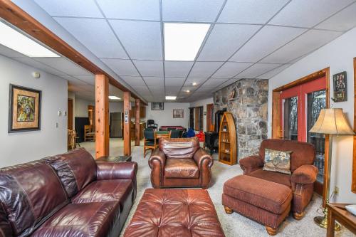 a living room with leather furniture and a stone wall at Slip Away Chalet in McHenry