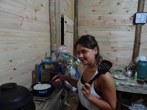 a woman holding a spatula in a kitchen at Spiritual Nature Farm - Sri Lanka in Matale