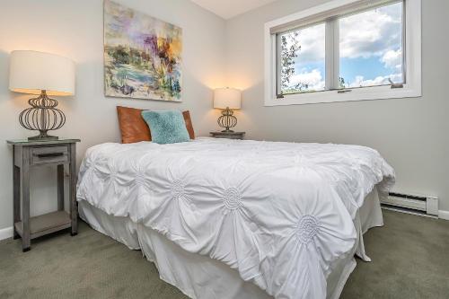 a bedroom with a white bed with two lamps and a window at Ski Harbor 11 in McHenry