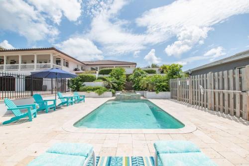 a swimming pool with blue chairs and a house at Island Time -- Oceanfront Bliss in Saint Augustine