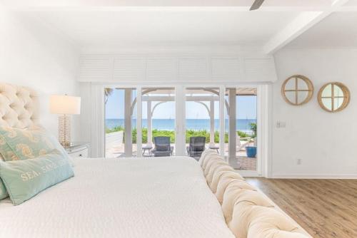a white bedroom with a large bed and a view of the ocean at Island Time -- Oceanfront Bliss in St. Augustine
