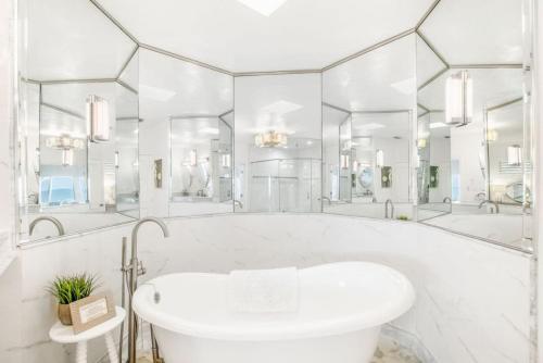 a white bathroom with a tub and mirrors at Island Time -- Oceanfront Bliss in St. Augustine