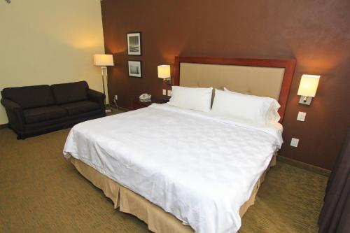 a hotel room with a large bed and a couch at Holiday Inn Leon by IHG in León