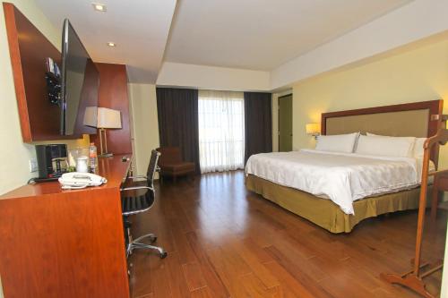 a hotel room with a bed and a desk with a computer at Holiday Inn Leon by IHG in León