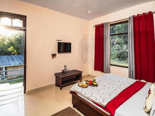 a bedroom with a bed and a table and a television at The Bunker Bir in Bīr