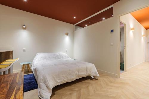 a white bedroom with a bed and a table at Charmant 3 pièces vue mer in Villefranche-sur-Mer