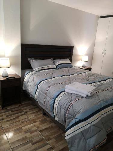 une chambre avec un grand lit et deux lampes dans l'établissement Lima Flats, à Lima
