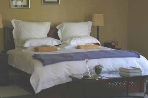 ein großes Bett mit weißer Bettwäsche und Kissen darauf in der Unterkunft Plumbago Guest House in Hazyview