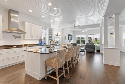 a kitchen with white cabinets and a bar with chairs at Cobalt Cottage History at your doorstep in St. Augustine