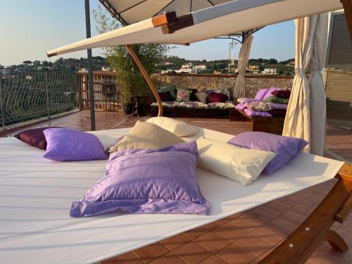 a bed with purple and white pillows on a balcony at DOMUS PARVA - Villa con bio-piscina, spa privata e appartamenti panoramici in Bacoli