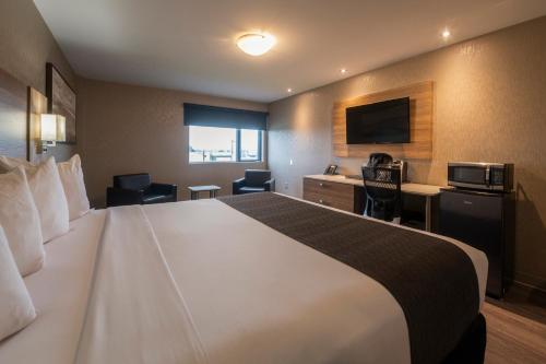 a hotel room with a large bed and a television at Hôtel & Suites Le Dauphin Québec in Quebec City