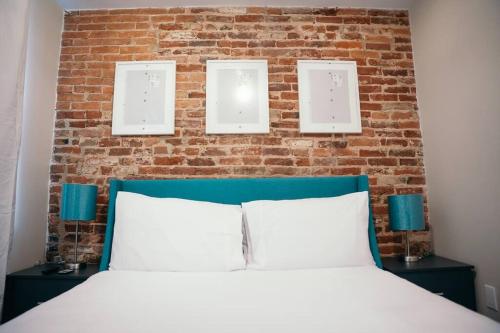 a bed with a brick wall and three lights above it at Fells Point Charm Doubled! in Baltimore