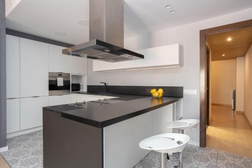 a kitchen with a black and white counter and stools at Sunny Beachside Haven 2 Bd In The Marina District in Barcelona