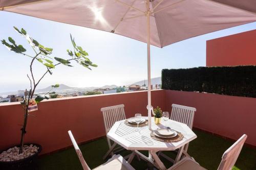 a table and chairs with an umbrella on a balcony at Acogedor ático con vistas al Atlántico in Arafo