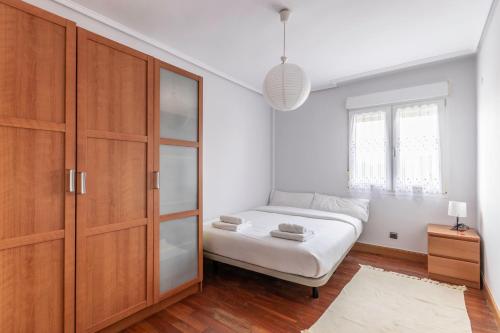 um quarto com uma cama e um armário de madeira em Sopela Etxea em Sopelana