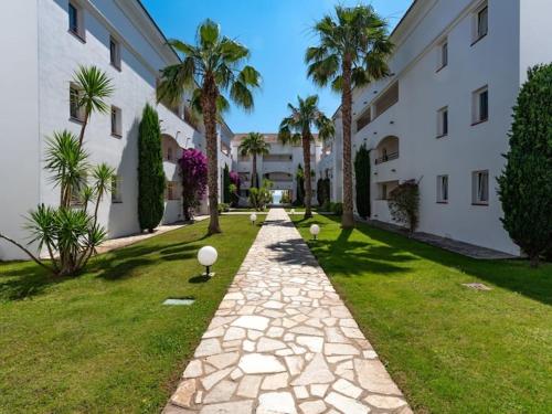 a walkway in front of a building with palm trees at Casa Emma les pieds dans l'eau in San-Nicolao