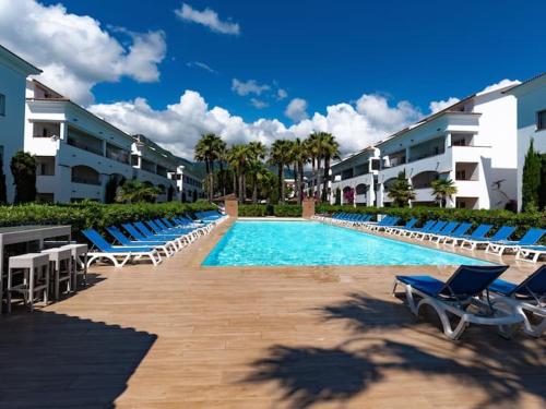 - une piscine avec des chaises longues bleues et des bâtiments dans l'établissement Casa Emma les pieds dans l'eau, à San-Nicolao