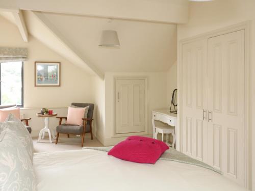 a bedroom with a white bed with a pink pillow on it at Ash Tree House in Salcombe