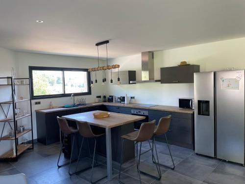 une cuisine avec une table et un réfrigérateur dans l'établissement Maison cosy 130m2, à Colombier