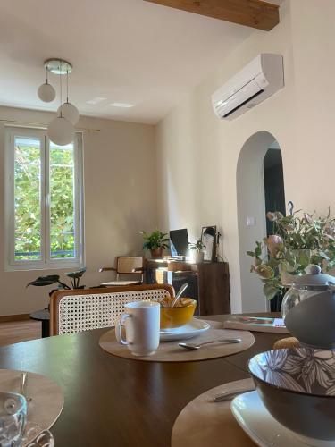 - une salle à manger avec une table en bois et des tasses dans l'établissement La Maison de Jeanne, à Narbonne